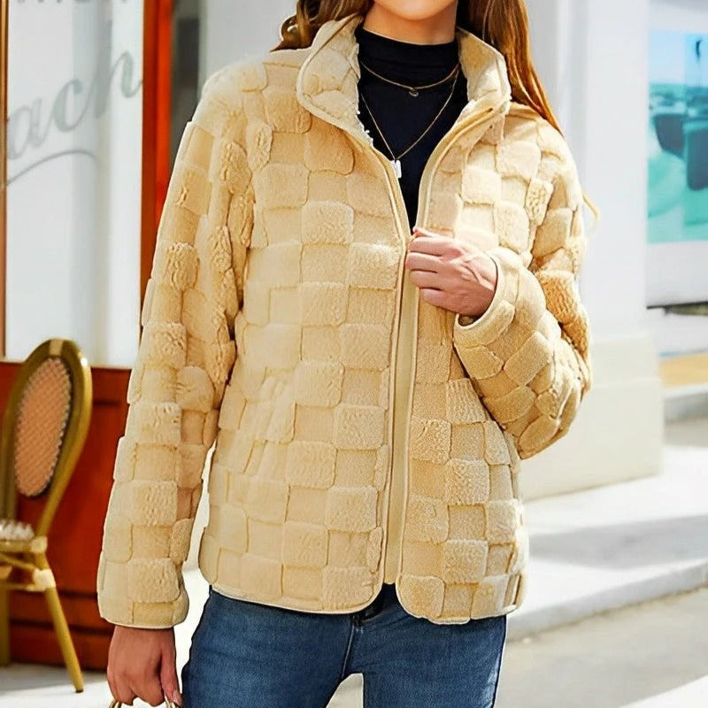 Veste en fausse fourrure beige à carreaux, portée par une personne en jean, devant un café. Mode automne-hiver, style décontracté et tendance.