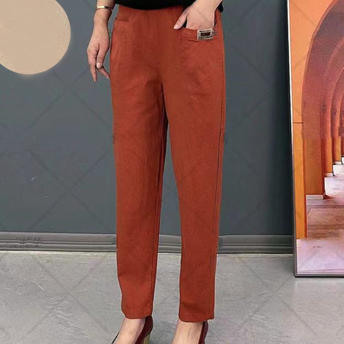 Pantalon femme orange élégant, coupe droite, avec ceinture décorative, porté avec des talons hauts. Mode automne, tendance vêtements féminins.
