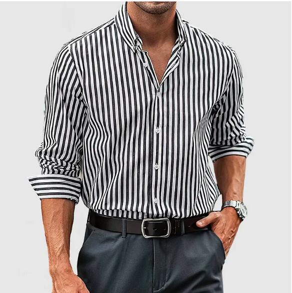 Homme portant une chemise rayée noir et blanc, manches retroussées, avec pantalon gris et ceinture noire. Mode masculine élégante et moderne.