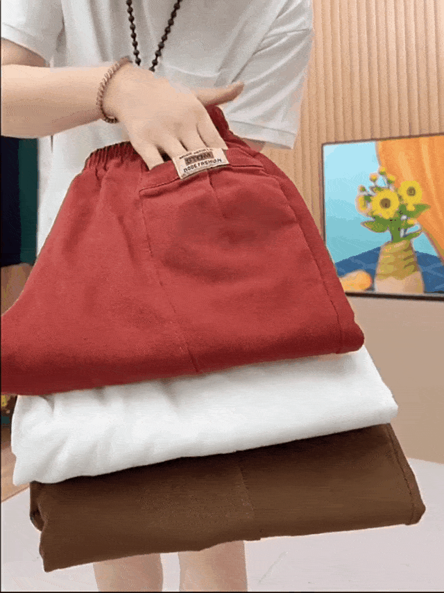 Homme tenant trois pantalons en lin: rouge, blanc, marron. Mode décontractée, vêtements d'été, style minimaliste, confort et élégance.