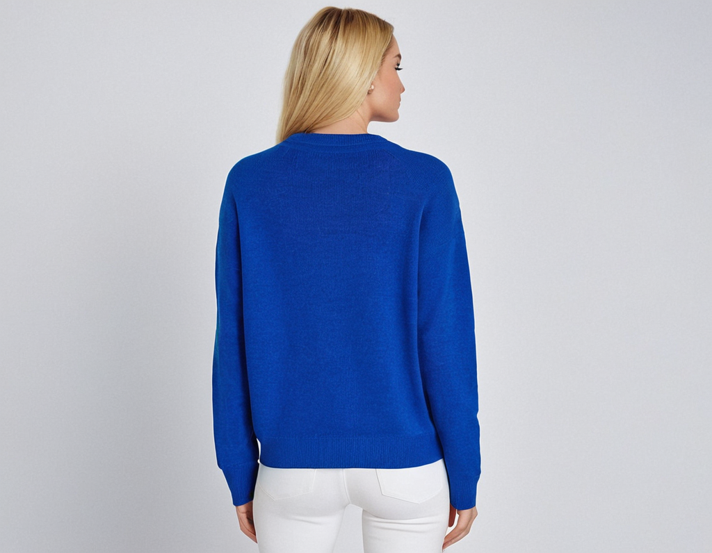 Femme blonde portant un pull bleu vif, vue de dos, sur fond blanc. Mode féminine, tenue décontractée, style moderne.