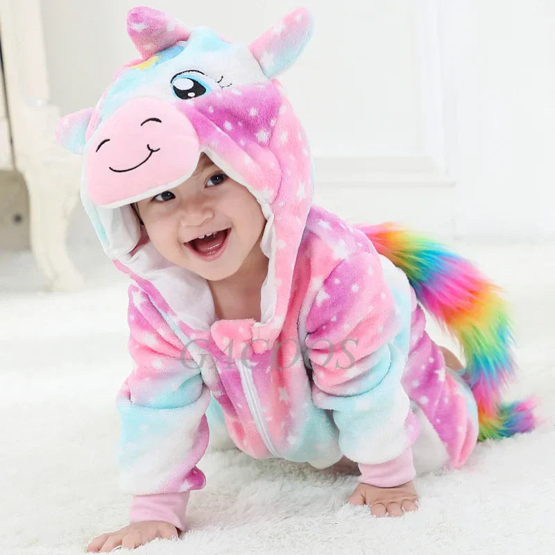 Bébé souriant en combinaison licorne multicolore, motif arc-en-ciel, oreilles et corne, sur fond blanc. Pyjama enfant mignon et confortable.
