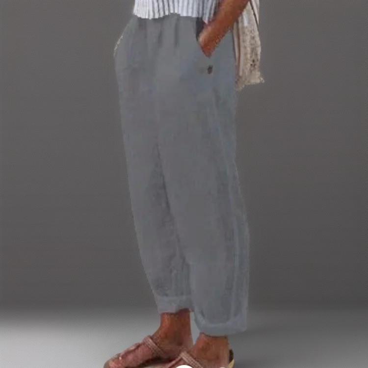 Pantalon ample gris en lin pour femme, style décontracté, avec poches latérales, associé à des sandales marron et un haut rayé.