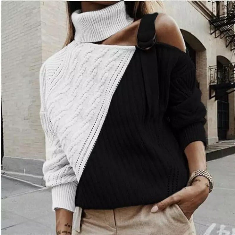Femme portant un pull asymétrique noir et blanc à col roulé, manches longues, style urbain chic, rue pavée en arrière-plan.