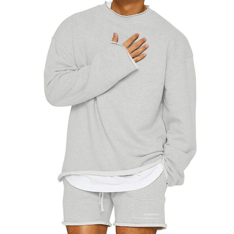 Homme portant un ensemble décontracté gris, composé d'un sweat-shirt ample et d'un short assorti, style moderne et confortable.