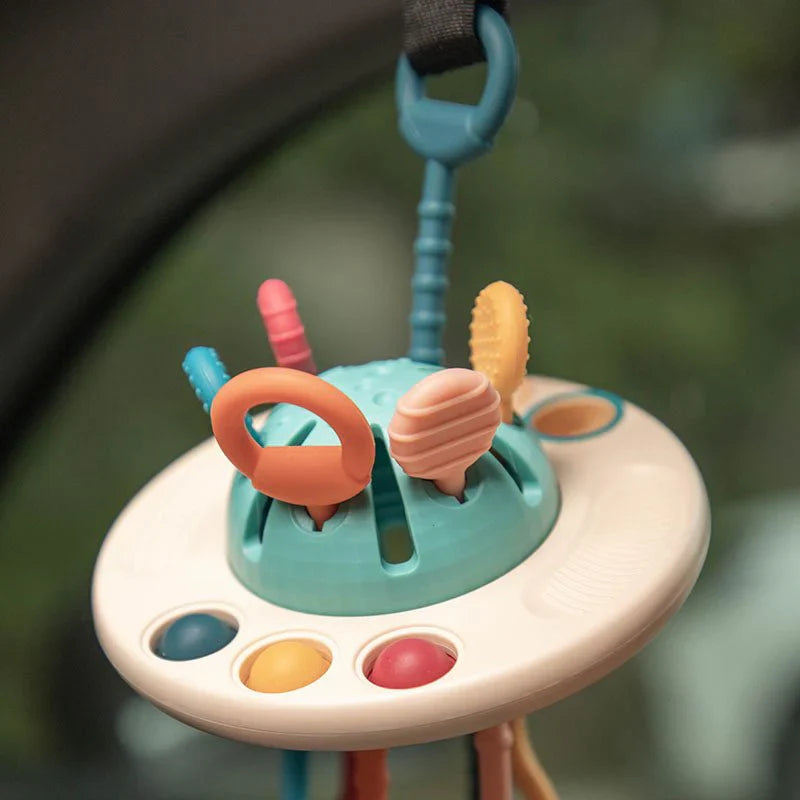 Jouet d'éveil suspendu pour bébé, multicolore, avec anneaux et formes texturées, idéal pour la stimulation sensorielle et le développement moteur.