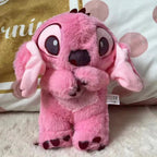 Peluche rose mignonne avec grands yeux, oreilles tombantes et pattes foncées, posée sur un lit. Jouet en peluche doux pour enfants.