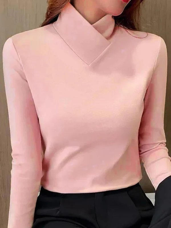 Femme portant un pull rose à col roulé croisé, manches longues, associé à un pantalon noir. Mode élégante et moderne pour l'automne.