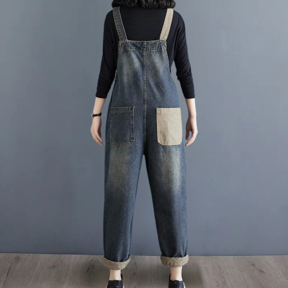 Combinaison en jean bleu pour femme, vue de dos, avec poches contrastées, sur fond gris. Mode décontractée, tendance, style urbain.