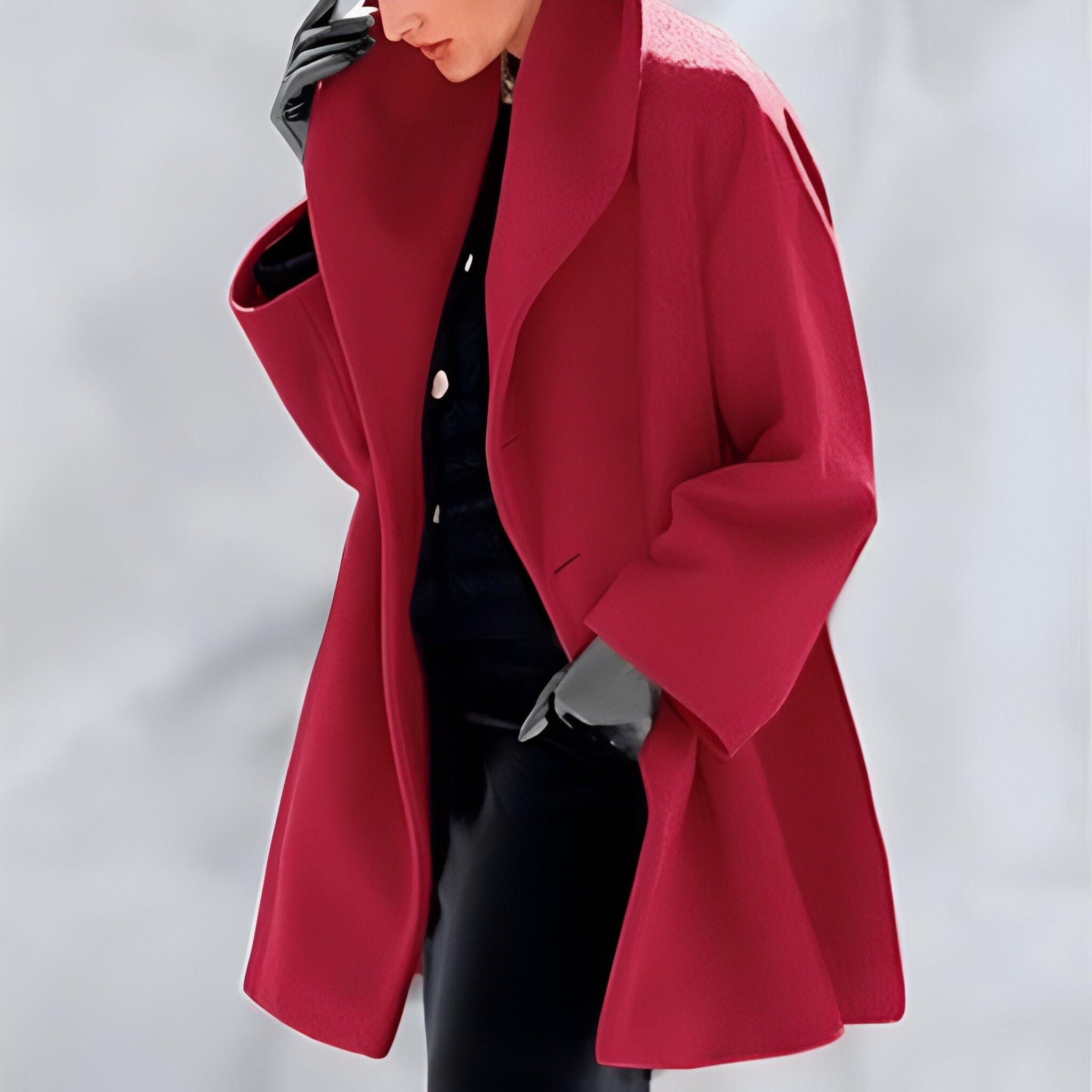 Manteau rouge élégant porté par une personne, avec des gants noirs et une tenue sombre en arrière-plan flou. Mode automne-hiver, style chic.