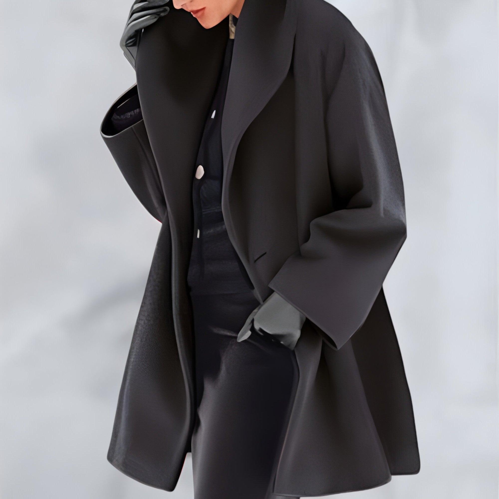 Manteau noir élégant sur mannequin, style moderne et minimaliste, mode automne-hiver, tissu luxueux, coupe ample, tendance vestimentaire chic.