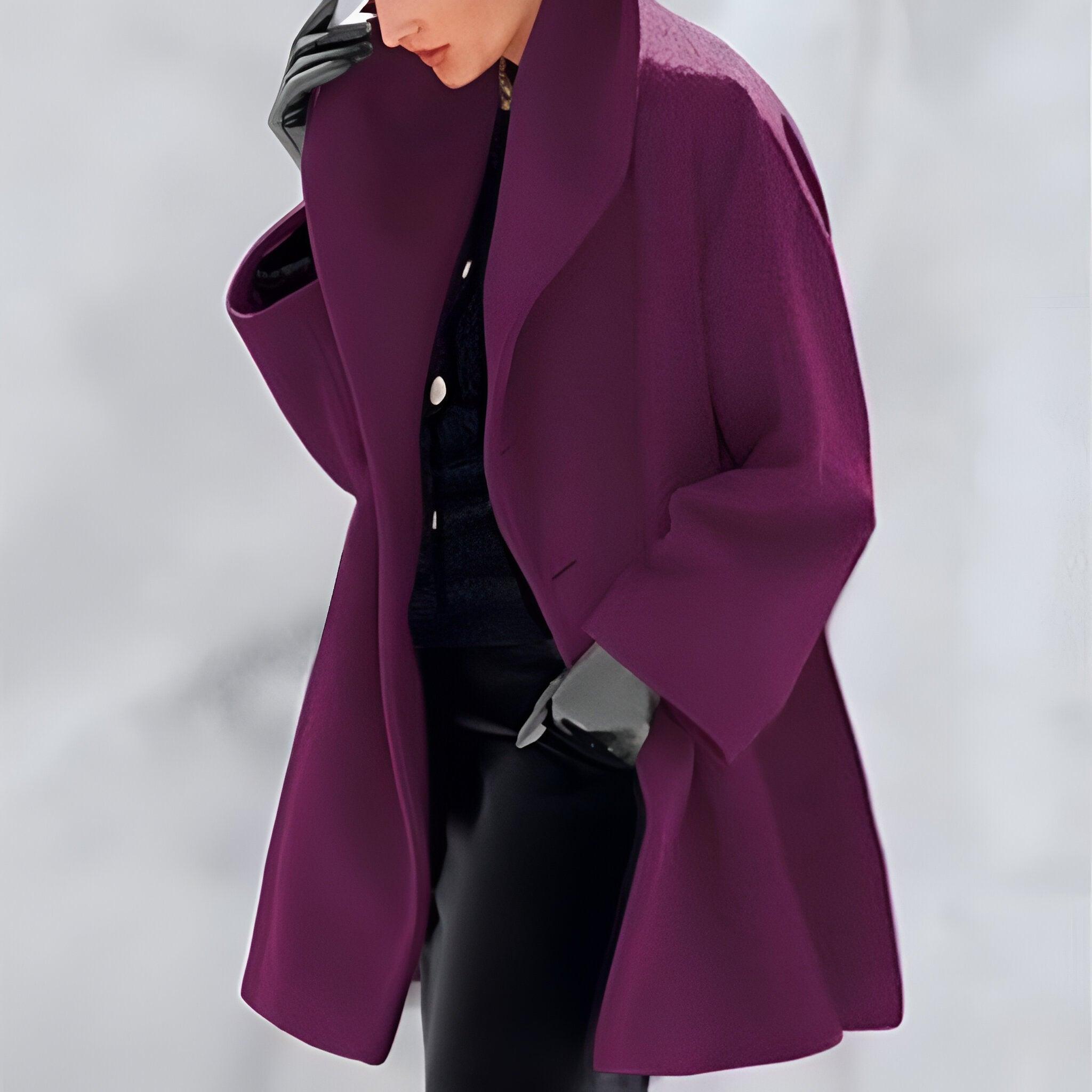 Personne portant un manteau violet élégant, gants noirs et tenue sombre, posant sur fond neutre. Mode automne-hiver, style chic et moderne.