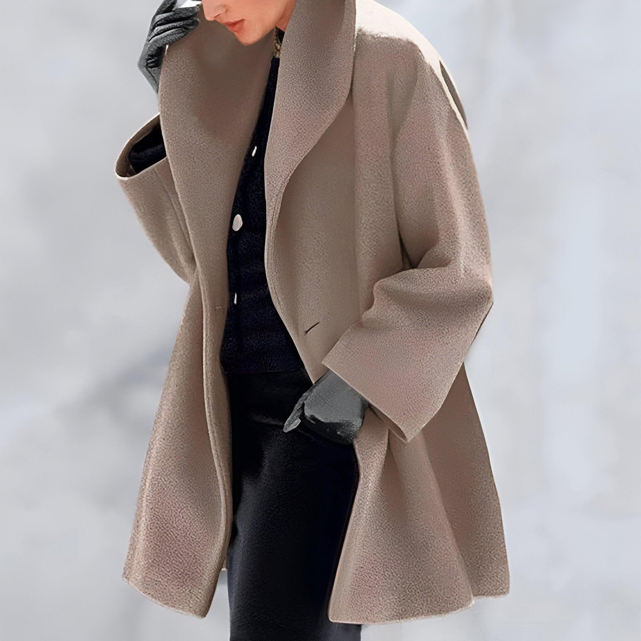 Manteau beige élégant pour femme, coupe ample, porté avec des gants noirs et un pull foncé. Mode automne-hiver, style chic et moderne.