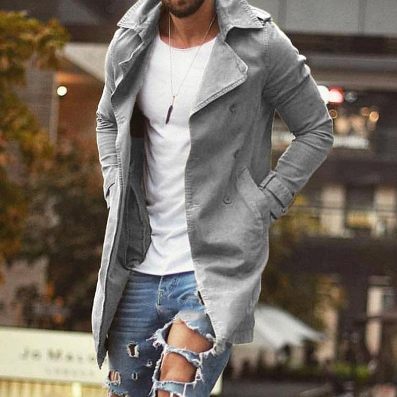 Homme portant un trench-coat gris élégant, t-shirt blanc et jeans déchirés tendance, en milieu urbain. Mode masculine moderne, style décontracté.
