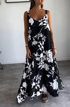 Robe longue noire et blanche à motifs floraux, portée par une femme. Style élégant et décontracté, idéal pour l'été. Accessoires minimalistes.