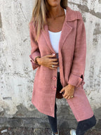 Femme portant un manteau rose élégant, sur fond de mur texturé. Mode automne, style décontracté, tendance féminine, tenue chic.