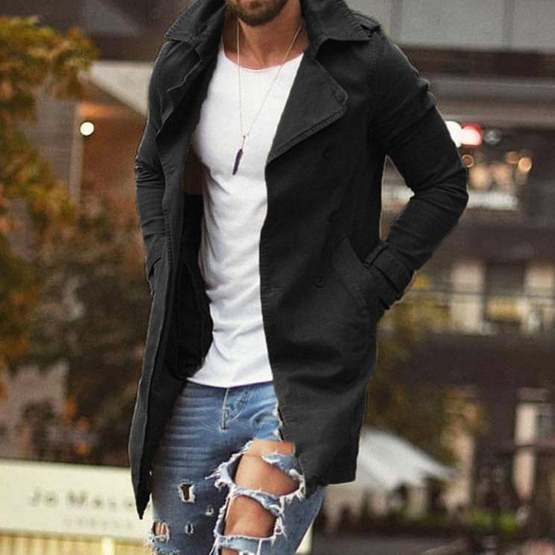 Homme portant un manteau noir élégant, t-shirt blanc et jeans déchirés tendance, en milieu urbain. Mode masculine, style décontracté chic.