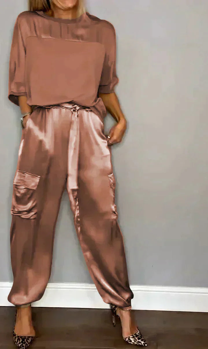 Femme portant un ensemble en satin rose, composé d'un haut ample et d'un pantalon cargo, avec des talons à motif léopard. Mode élégante et tendance.