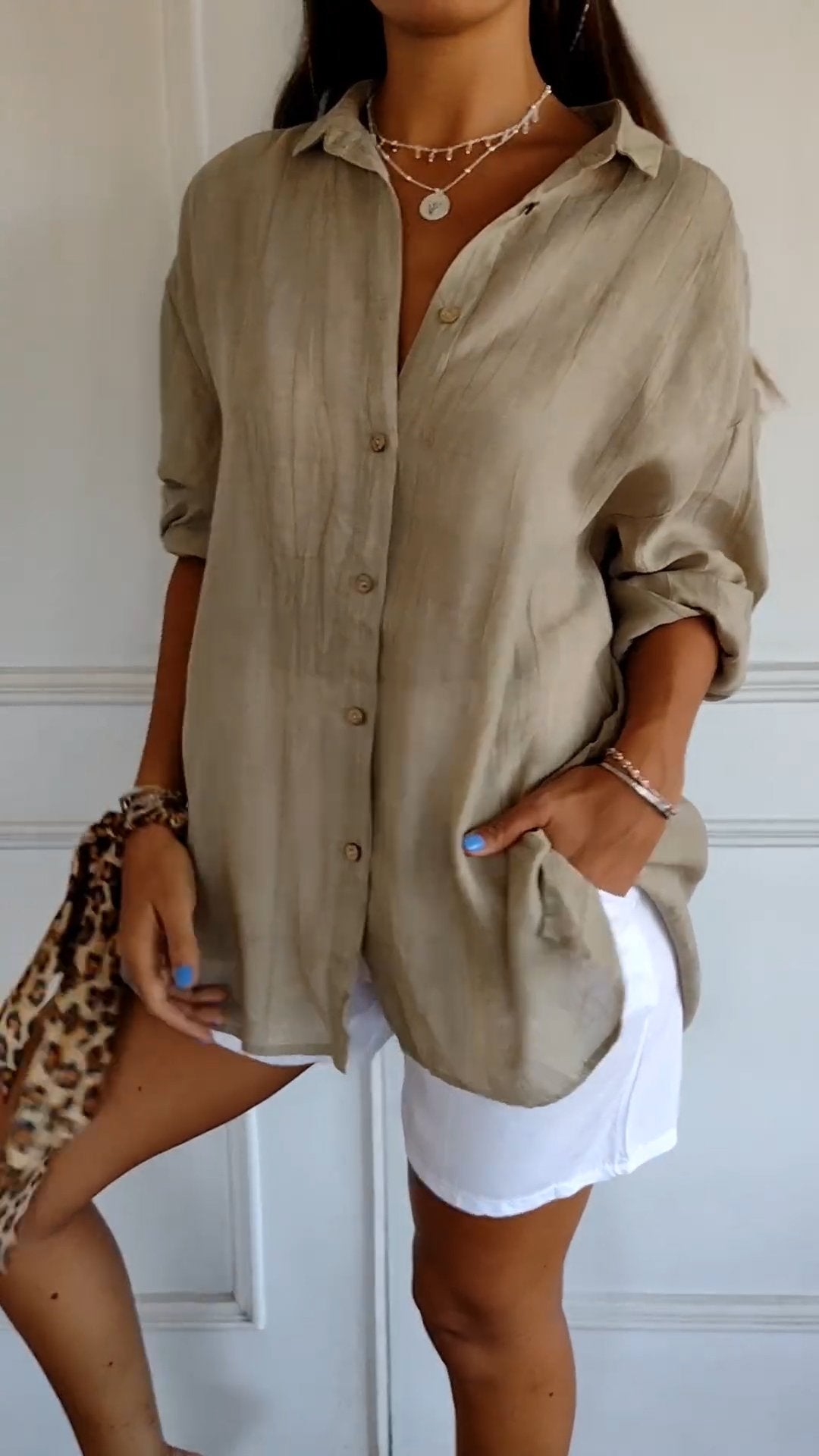 Chemise beige en lin pour femme, manches retroussées, portée avec short blanc. Style décontracté, tendance mode estivale, accessoires léopard.