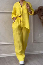 Femme portant un ensemble chemise et pantalon en lin jaune vif, style décontracté, avec baskets blanches, posant dans un intérieur moderne.