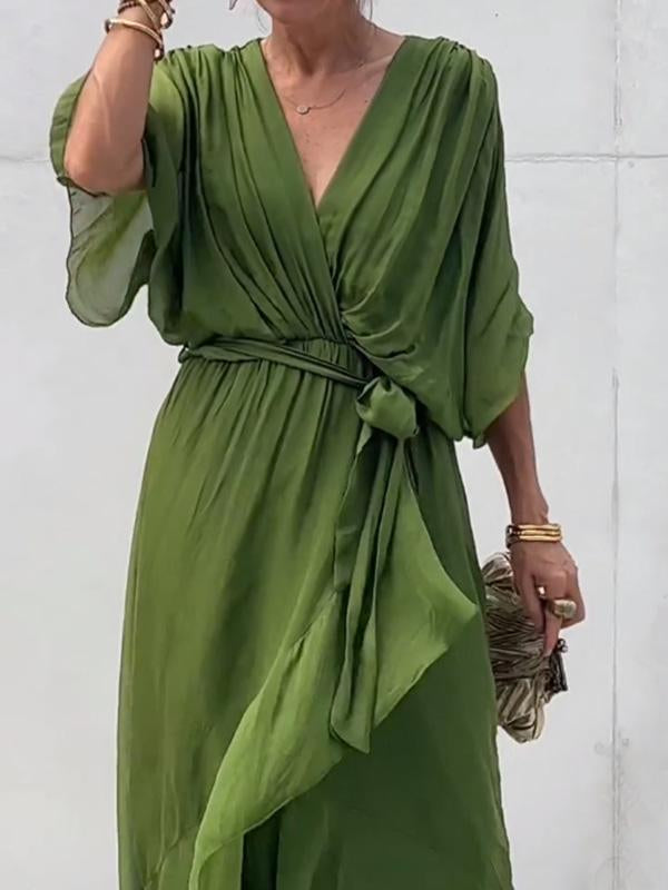 Robe verte élégante avec manches amples et ceinture nouée, tenue chic pour femme, accessoirisée de bracelets dorés et pochette zébrée.