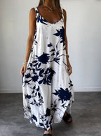 Robe longue blanche à motifs floraux bleus, sans manches, portée par une femme. Style décontracté, idéal pour l'été. Mode féminine élégante.