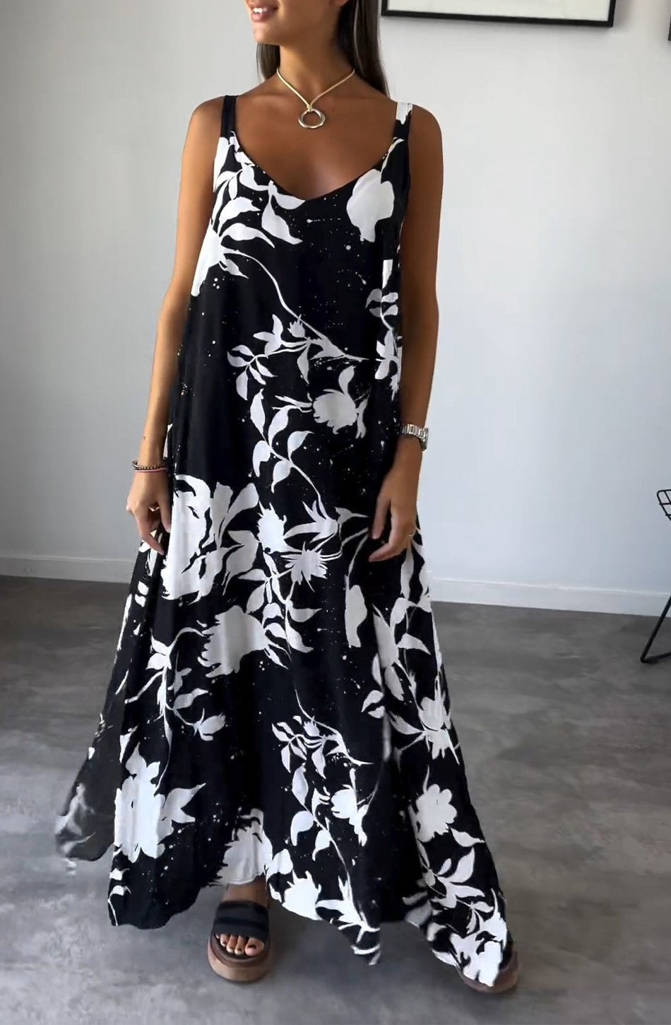 Robe longue noire et blanche à motifs floraux, portée par une femme. Style élégant et décontracté, idéal pour l'été. Accessoires minimalistes.