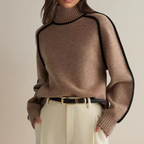 Femme portant un pull en laine marron à col roulé avec bordures noires, ceinture noire et pantalon beige. Mode automne-hiver élégante et chic.