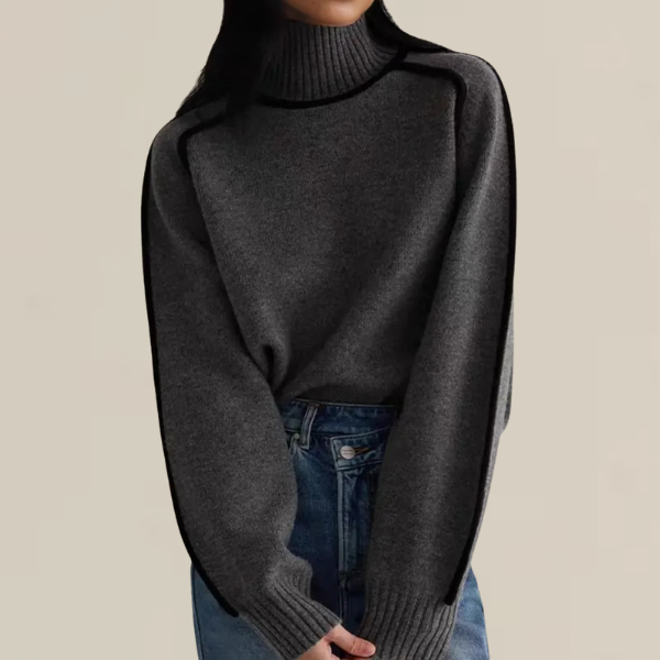 Femme portant un pull en laine gris à col roulé avec des manches longues, associé à un jean bleu. Mode automne-hiver, style décontracté et élégant.