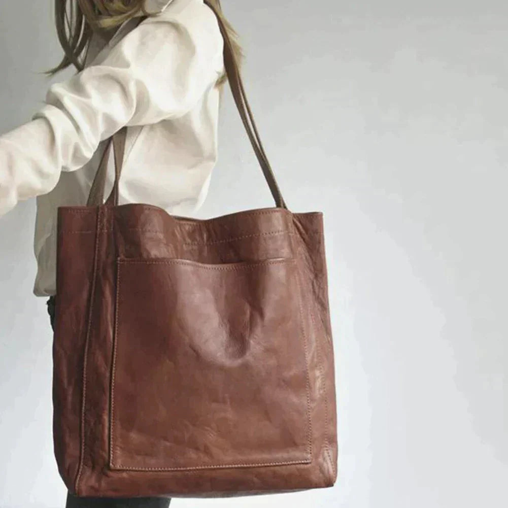 Sac cabas en cuir marron porté par une femme, design élégant et spacieux, idéal pour le shopping ou le quotidien. Accessoire mode tendance.