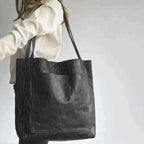 Sac cabas en cuir noir porté par une femme en chemise blanche, design élégant et moderne, accessoire mode tendance pour toutes occasions.