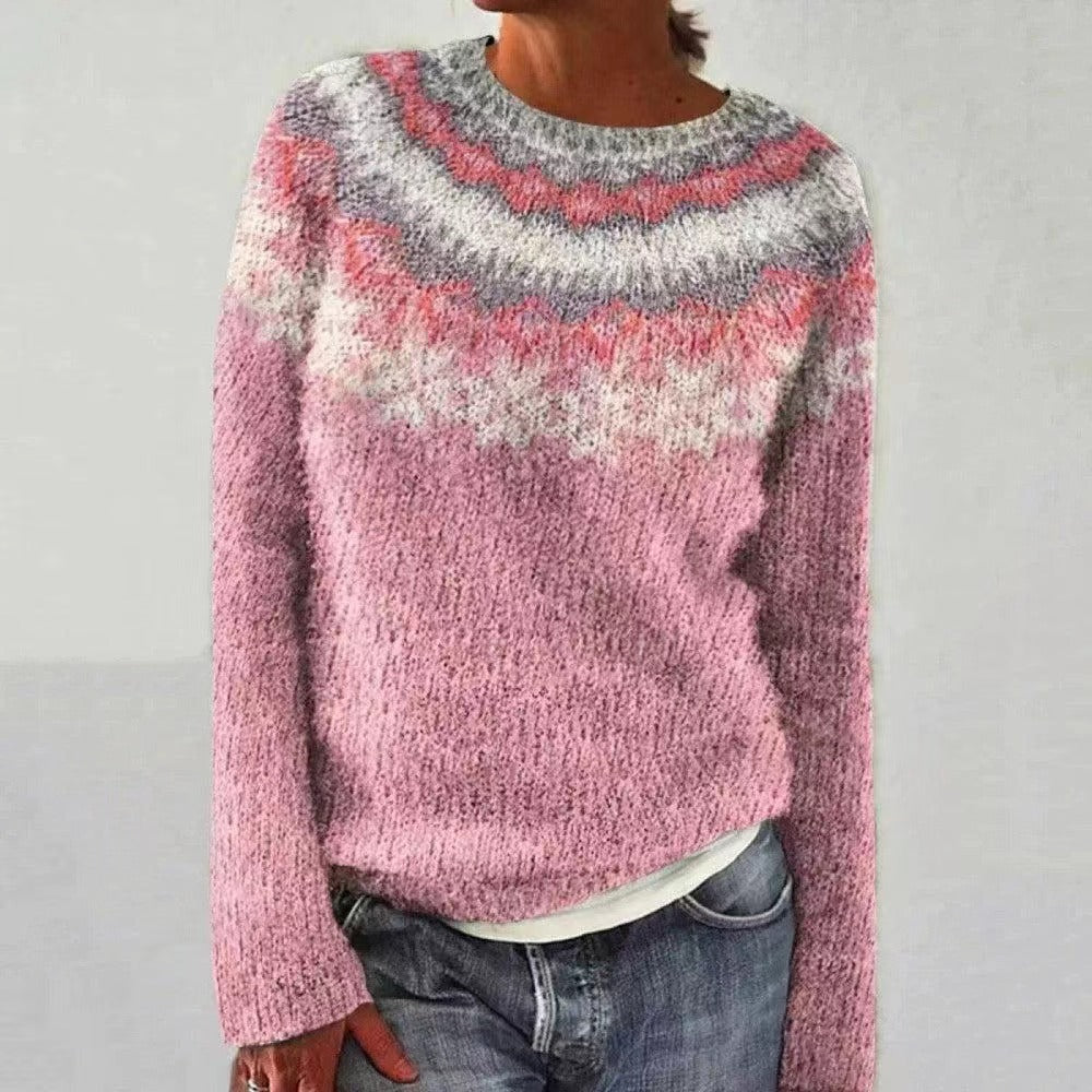 Pull-over tricoté rose avec motif nordique, manches longues, porté par une personne en jean. Mode automne-hiver, style décontracté et confortable.