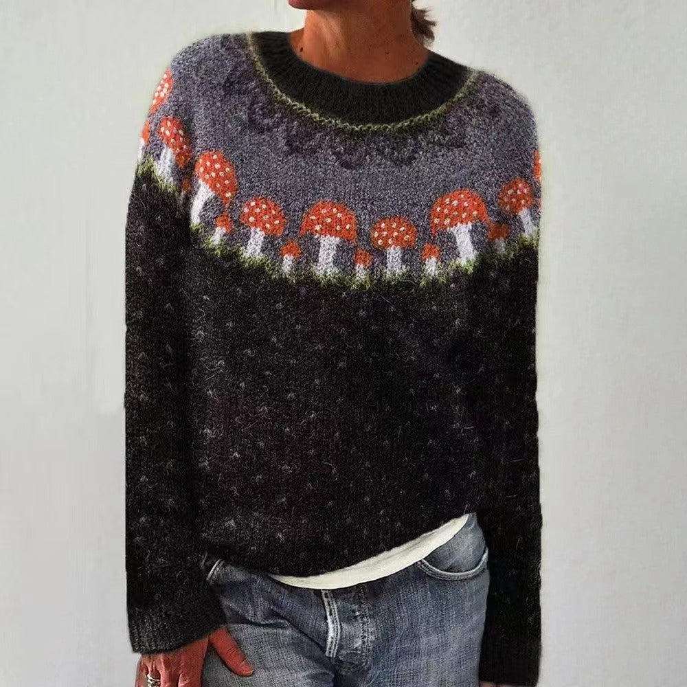 Pull-over en laine avec motif champignons rouges et blancs, col rond, manches longues, porté par une personne en jean. Mode automne-hiver tendance.