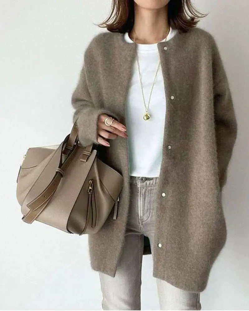 Femme portant un manteau en laine marron, t-shirt blanc, jean gris, et sac à main beige. Mode automne, style décontracté chic, accessoires élégants.