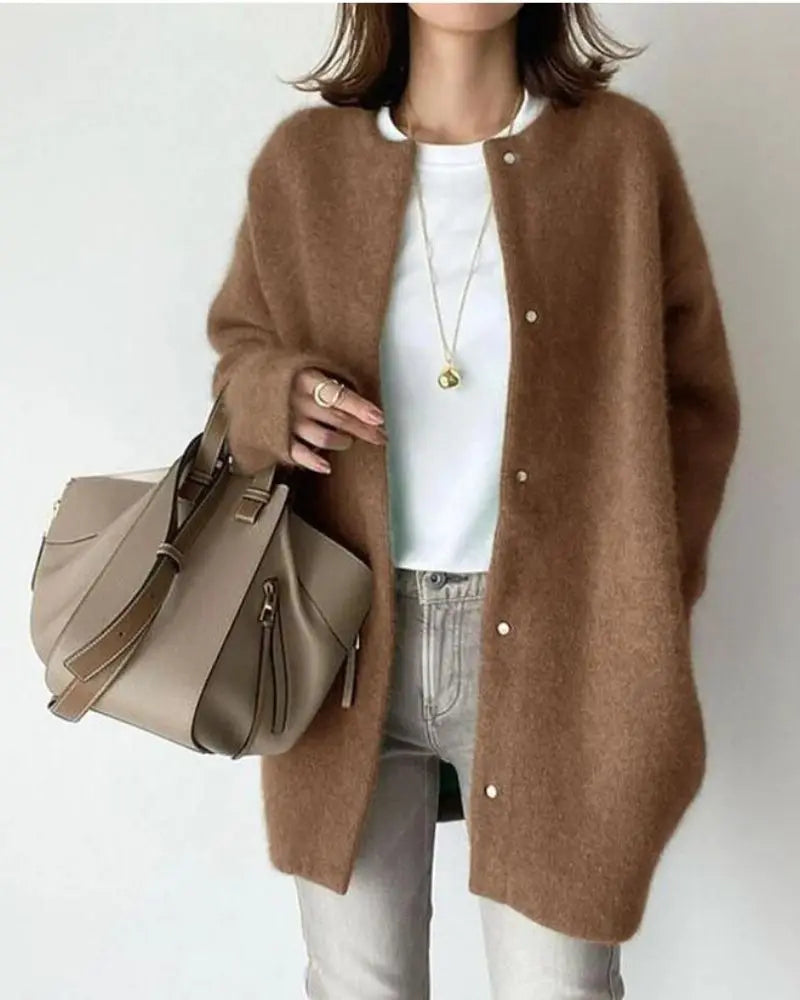 Femme portant un cardigan marron en laine, t-shirt blanc, jean gris, sac à main beige; mode automne-hiver, style décontracté chic.
