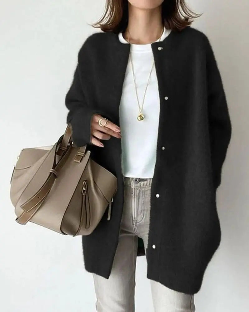 Femme portant un cardigan noir, t-shirt blanc, jean gris, avec un sac à main beige. Mode automne chic, tenue décontractée élégante.