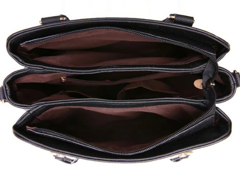 Sac à main noir en cuir avec trois compartiments zippés, doublure marron. Accessoire mode femme, rangement pratique, élégant et fonctionnel.