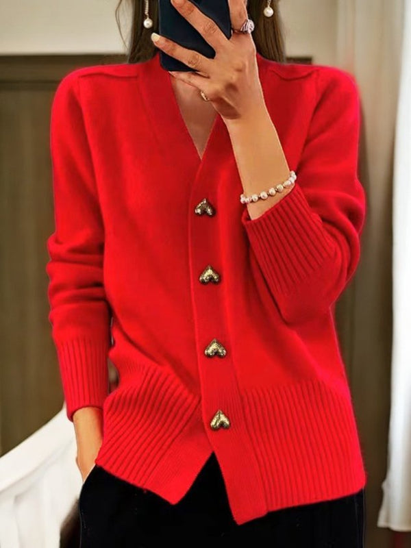 Femme portant un cardigan rouge vif avec boutons dorés en forme de cœur, manches longues, col en V, accessoirisé d'un bracelet perlé.