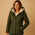 Femme portant une veste verte à capuche doublée de fourrure, sur fond beige. Mode automne-hiver, style décontracté, vêtement chaud et élégant.