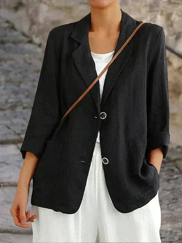 Veste noire élégante pour femme, manches longues, portée sur un t-shirt blanc, avec un sac en bandoulière marron. Mode féminine chic et décontractée.