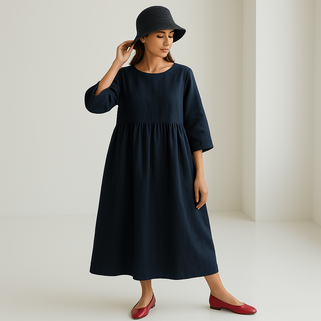 Robe longue bleu marine en lin, manches trois-quarts, portée par une femme avec chapeau gris et chaussures rouges, style minimaliste et élégant.