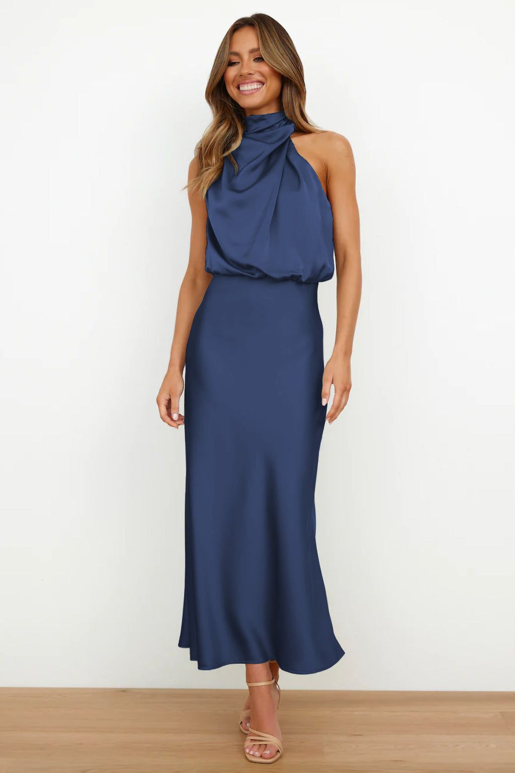 Robe longue bleu marine élégante, sans manches, col drapé, portée par une femme souriante. Mode féminine chic, tenue de soirée tendance.