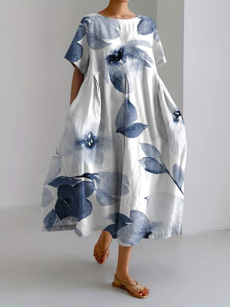 Robe longue blanche à motifs floraux bleus, manches courtes, coupe ample, style décontracté, portée avec des sandales. Mode féminine élégante.