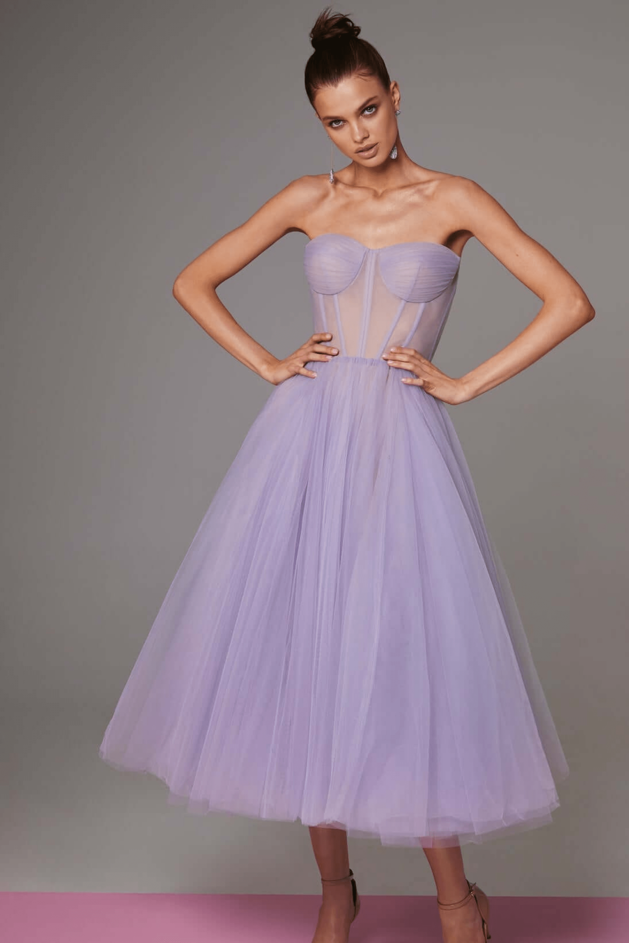 Robe bustier en tulle lavande, longueur mi-mollet, élégante et moderne, portée par une femme posant sur fond gris. Mode féminine chic.