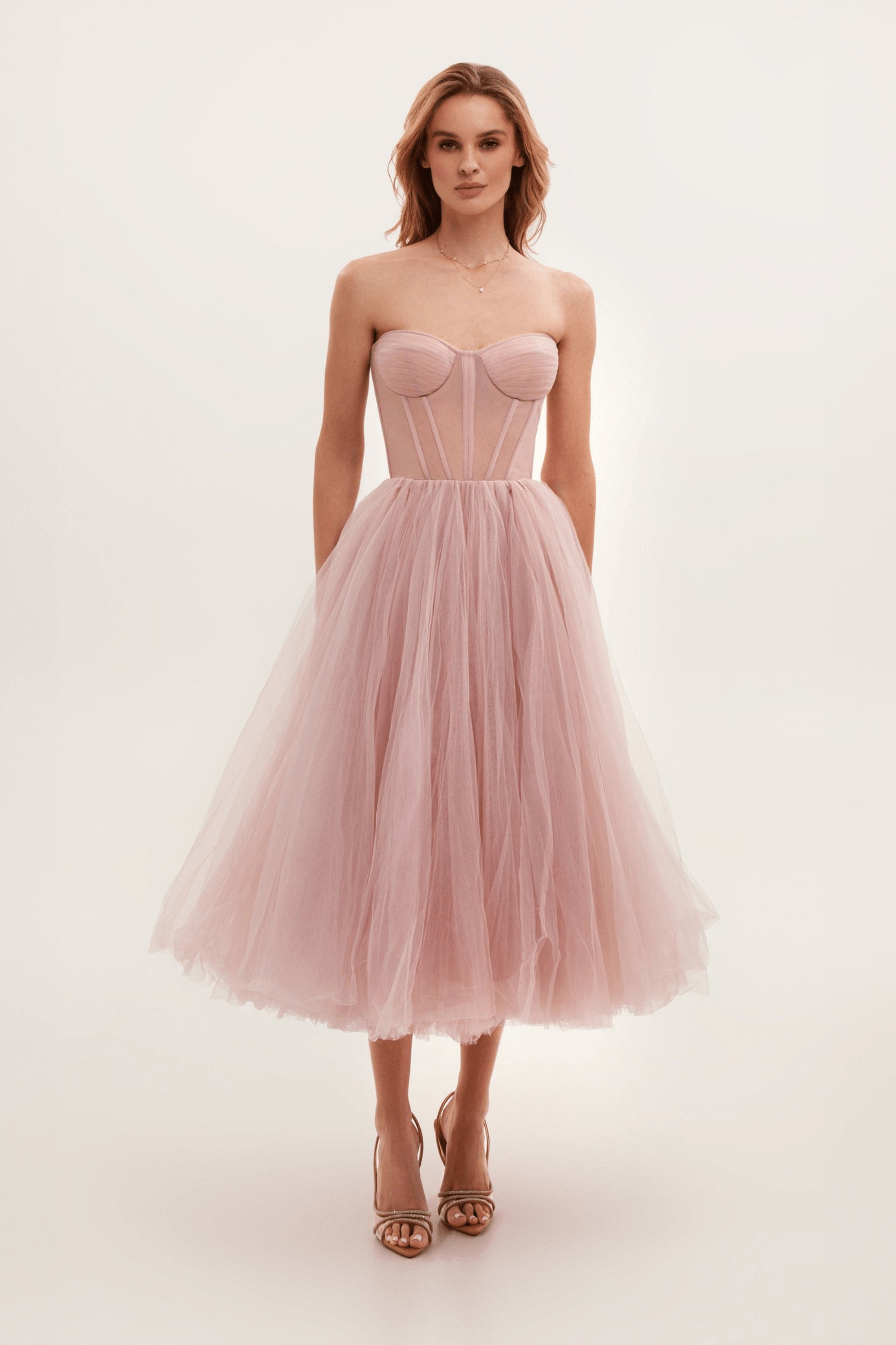 Robe bustier rose en tulle, longueur mi-mollet, portée par une femme. Mode élégante, tenue de soirée, style romantique, tendance féminine.