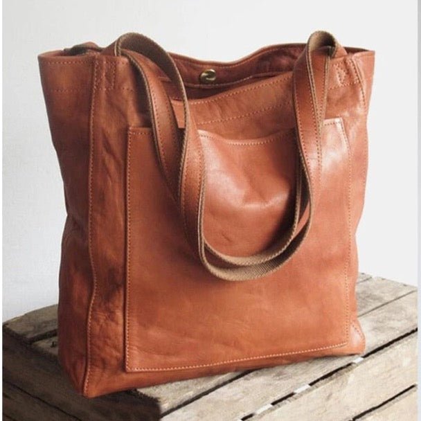 Sac à main en cuir marron sur une table en bois, design élégant et pratique, idéal pour la mode féminine. Accessoire tendance et fonctionnel.
