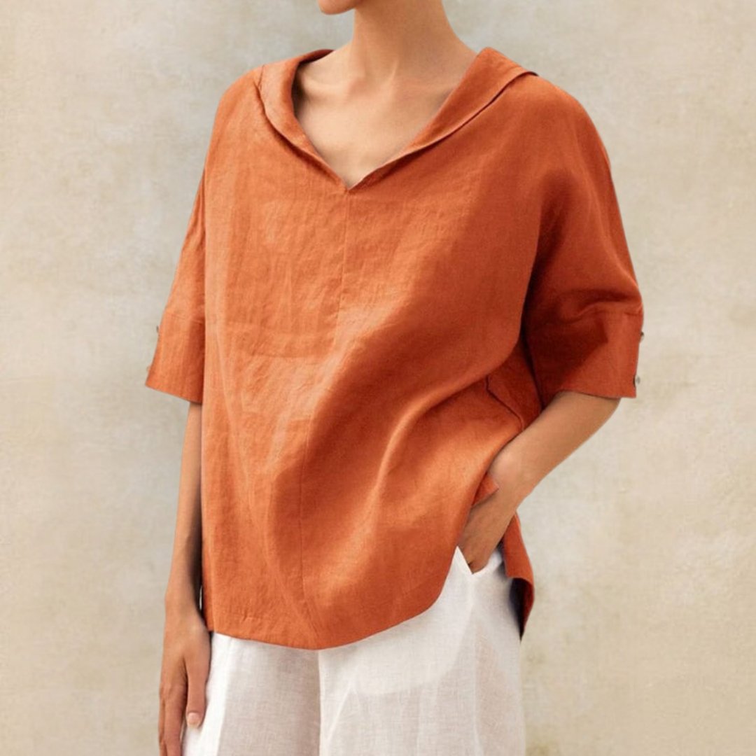 Blouse en lin orange à manches courtes, col ouvert, portée par une femme, associée à un pantalon blanc. Mode décontractée, style estival.