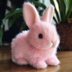 Lapin en peluche rose sur une table en bois, avec des plantes en arrière-plan. Jouet doux et mignon, idéal pour la décoration ou les enfants.
