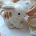 Enfant caressant un lapin en peluche blanc doux, jouet mignon, sur une table avec des perles, symbolisant tendresse et jeu créatif.