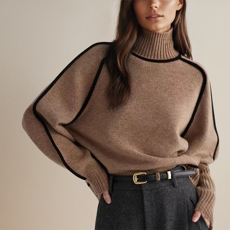 Femme portant un pull en laine beige à col roulé, manches larges et détails noirs, ceinturée, avec un pantalon gris. Mode automne chic et élégante.